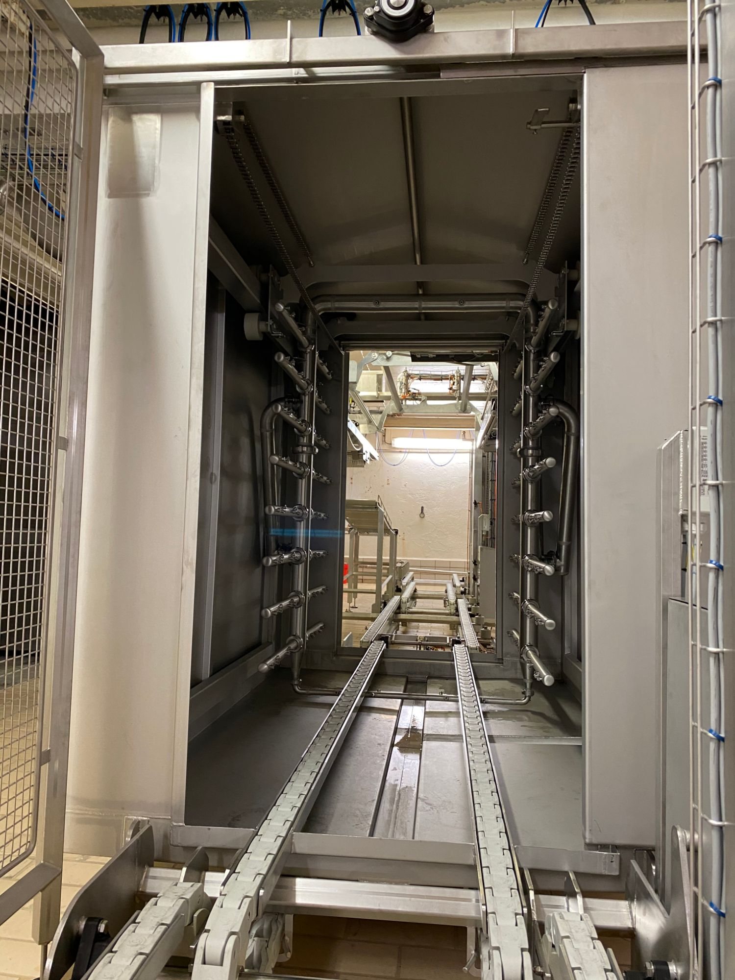 Washer with nozzle pipes and chain conveyor.